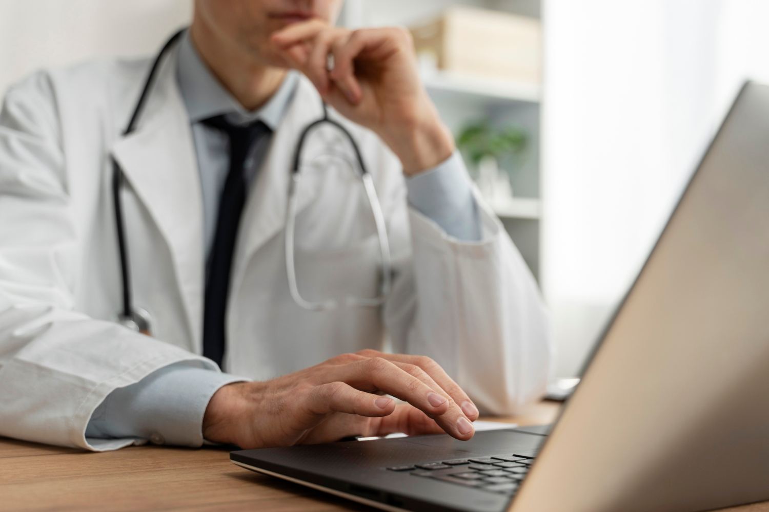 Médico mexendo no notebook em seu consultório